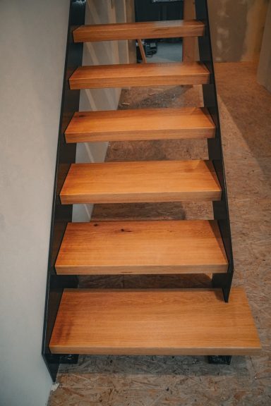 Geradläufige Treppe mit massiven Eichenstufen und schlanken Stahlwangen – modern, stabil, zeitlos. Blick auf den Angang der Treppe.