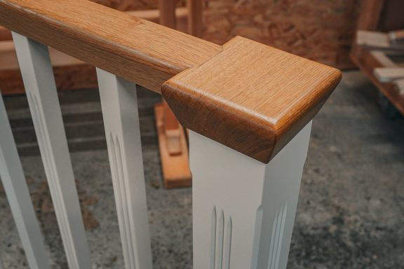 Ein Profiliertes Geländer mit passendem Pfosten, weiß lackiert. Der Handlauf gefertigt in Eiche.