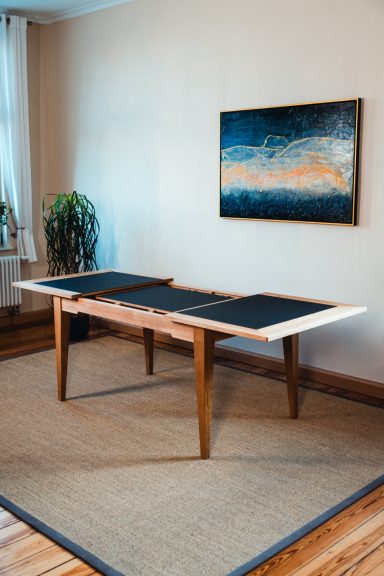Ausziehbarer Esstisch in Eiche und schwarzem Linoleum.