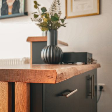 Ein Frisörtresen aus schwarz lackiertem MDF und massiver Eichenplatte mit Naturkante. Detailbild der Tresenplatte